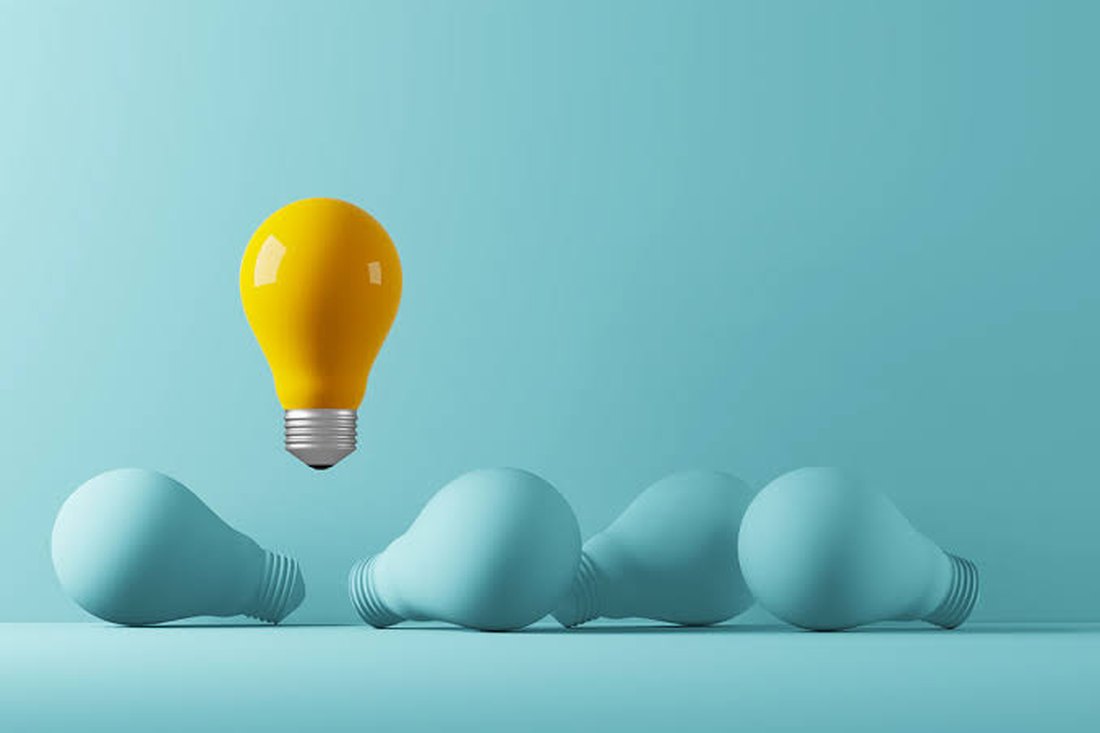 A yellow lightbulb lifting above a row of plain teal bulbs